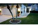 Home's front exterior featuring a well-manicured lawn, palm trees, and exterior lighting at 5661 Parkview Lake Dr, Orlando, FL 32821
