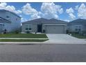 Beautiful single-story home featuring a gray exterior, a two-car garage, and manicured landscaping at 568 Meadow Bend Dr, Davenport, FL 33837