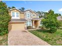 Two-story home showcasing a stone facade, complemented by a brick driveway and verdant landscaping at 771 Cavan Dr, Apopka, FL 32703