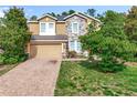 Charming two-story home featuring a stone facade, brick driveway, and lush landscaping at 771 Cavan Dr, Apopka, FL 32703