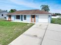 A single-story home with a garage and an elongated driveway surrounded by a green lawn at 925 Roswell Ter, Deltona, FL 32738