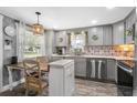 Well-lit kitchen features stainless steel appliances, gray cabinets, and eat-in table with designer backsplash at 1422 Indiana Ave, St Cloud, FL 34769