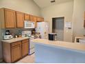 Bright kitchen featuring white appliances, light wood cabinets, and an extended counter space, perfect for casual dining at 2141 Fawn Meadow Cir, St Cloud, FL 34772