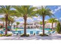 Spacious community pool surrounded by palm trees, lounge chairs, and a splash pad for children at 2525 Shanti Dr, Kissimmee, FL 34746