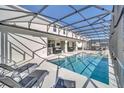 Stunning screened-in pool area featuring lounge chairs, an outdoor kitchen, and clear blue water at 2525 Shanti Dr, Kissimmee, FL 34746