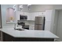 Well-lit kitchen featuring white cabinets, stainless steel appliances, and an island with a quartz countertop at 3428 Soho St # 208, Orlando, FL 32835