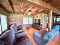 Comfortable living room featuring log walls, hardwood floors, a ceiling fan, and cozy seating at 4075 Packard Ave, St Cloud, FL 34772
