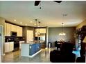 Modern kitchen features stainless steel appliances, a kitchen island, and an adjacent dining area at 5519 Braken Fern Way, Leesburg, FL 34748
