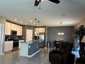 Modern kitchen features stainless steel appliances, a kitchen island, and an adjacent dining area at 5519 Braken Fern Way, Leesburg, FL 34748