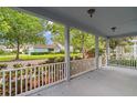 Inviting covered porch with white railing offering neighborhood views and lush landscaping at 6905 Beargrass Rd, Harmony, FL 34773