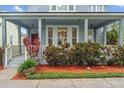 Inviting front porch with stylish columns, vibrant plants and a red front door at 6905 Beargrass Rd, Harmony, FL 34773