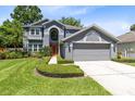 Inviting two-story home with a lush green lawn, mature landscaping, and an attached two-car garage at 716 Timberwilde Ave, Winter Springs, FL 32708