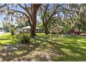 Spacious front yard with mature trees and lush landscaping, showcasing the homes and neighborhood at 1101 Oregon Ave, St Cloud, FL 34769