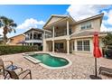 A backyard pool and spa with a brick patio is adjacent to the home and an adjacent covered outdoor living space at 1225 Radiant St, Reunion, FL 34747