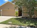 Two-story tan home with a tree-lined lawn, front entrance, and two-car garage providing great curb appeal at 2106 Congress Ln, St Cloud, FL 34769