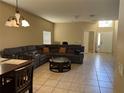 Open living room with tile flooring, a gray sofa, and natural light flowing through the adjacent entrance at 2106 Congress Ln, St Cloud, FL 34769