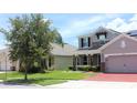Street view of a two-story home with a three car garage, stone accents, and a well-manicured lawn at 2805 Carter Grove Ln, Kissimmee, FL 34741