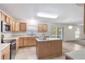 Well-lit kitchen features wood cabinets, center island, stainless appliances, and adjacent living area at 364 Fish Hawk Dr, Winter Haven, FL 33884