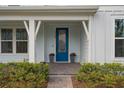 Inviting front porch with a vibrant blue door, complemented by potted plants and lush landscaping at 6522 Rover Way, St Cloud, FL 34771