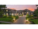 Charming home exterior with manicured landscaping and warm sunset lighting, stone accents and inviting entrance at 9905 Lanai View Ct, Windermere, FL 34786