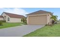 View of the home's two-car garage, spacious driveway, and tidy landscaping at 1197 E Grove Ave, Lake Wales, FL 33853