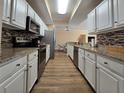 Modern kitchen features white cabinets, granite countertops, stainless steel appliances, and wood-look flooring at 12021 Villanova Dr # 111, Orlando, FL 32837