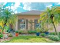 Inviting home exterior featuring lush tropical landscaping, including mature palms and vibrant plants surrounding the windows at 142 Largo Dr, Poinciana, FL 34759