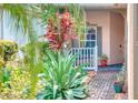 Inviting front porch, complemented by verdant tropical landscaping, creating a serene entrance at 142 Largo Dr, Poinciana, FL 34759