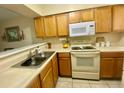 Cozy kitchen with wooden cabinets, white appliances and countertops, and stainless steel sink at 167 Scottsdale Sq # 167, Winter Park, FL 32792