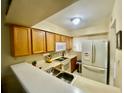 Well-lit kitchen featuring wooden cabinets, white appliances and a convenient breakfast bar at 167 Scottsdale Sq # 167, Winter Park, FL 32792