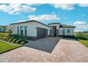 Gorgeous home exterior with stone accents, a three car garage, and brick driveway at 224 Valencia Ridge Dr, Auburndale, FL 33823
