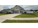 A two-story house with a light gray exterior, attached two-car garage, and a well-maintained green lawn at 2508 W End Dr, St Cloud, FL 34772