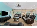 Spacious living room with leather furniture, ceiling fan, and sliding glass doors overlooking the backyard at 256 Yellow Snapdragon Dr, Davenport, FL 33837