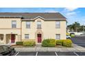 Tan two-story townhouse featuring a red front door, tidy landscaping, and convenient parking at 2867 Club Cortile Cir, Kissimmee, FL 34746