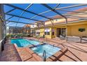 The backyard features a screened-in pool and hot tub with brick patio and lounge furniture at 477 Orange Cosmos Blvd, Davenport, FL 33837