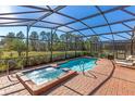 Screened-in pool and hot tub on brick patio with a view of treed backyard at 477 Orange Cosmos Blvd, Davenport, FL 33837