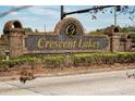 Elegant brick entrance sign for Crescent Lakes, surrounded by lush landscaping at 5100 Violet Ln, Kissimmee, FL 34758