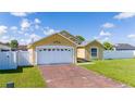 Yellow home with two-car garage, well maintained lawn, and white picket fence at 5100 Violet Ln, Kissimmee, FL 34758