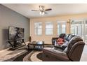 Comfortable living room with a leather reclining sofa, large windows, and a modern ceiling fan at 5231 Wildwood Way, Davenport, FL 33837