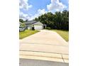 Long driveway leading up to a charming single-story home with a well-manicured lawn and a two-car garage at 144 Foxtail Loop, Davenport, FL 33837