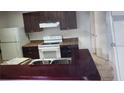 Kitchen with stainless steel sink, white appliances, dark wood cabinets and breakfast bar at 2002 Cascades Blvd # 108, Kissimmee, FL 34741