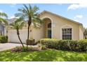 Inviting single-story home boasting a lush lawn, mature palm trees, and a vibrant blue front door at 2263 Mallory Cir, Haines City, FL 33844