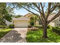 Well-maintained home featuring an attached two-car garage, green lawn, and mature shade tree at 2263 Mallory Cir, Haines City, FL 33844