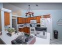 Open-concept kitchen with wood cabinets, white appliances, and a breakfast bar area at 2773 Woodstream Cir, Kissimmee, FL 34743