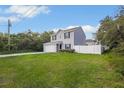 View of a two-story house with a white fence, showcasing its well-maintained lawn and quiet neighborhood at 303 Anchovie Ct, Poinciana, FL 34759