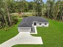 Aerial view of a well-maintained property with lush green grass, a long driveway, and a spacious two-car garage at 33 Peterlee Ct, Kissimmee, FL 34758