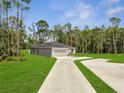 Landscaped property featuring a long driveway and a modern home design surrounded by lush greenery at 33 Peterlee Ct, Kissimmee, FL 34758