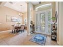 Elegant foyer showcasing a dining table, chandelier, tile flooring and a front door with decorative glass at 3856 Shoreside Dr, Kissimmee, FL 34746