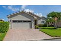 Well-maintained single-story home with brick driveway, two-car garage, and lush green lawn at 4056 Ashton Club Dr, Lake Wales, FL 33859