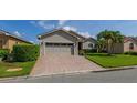 Single-story home with brick driveway, two-car garage, and beautifully landscaped front yard with palm trees at 4056 Ashton Club Dr, Lake Wales, FL 33859